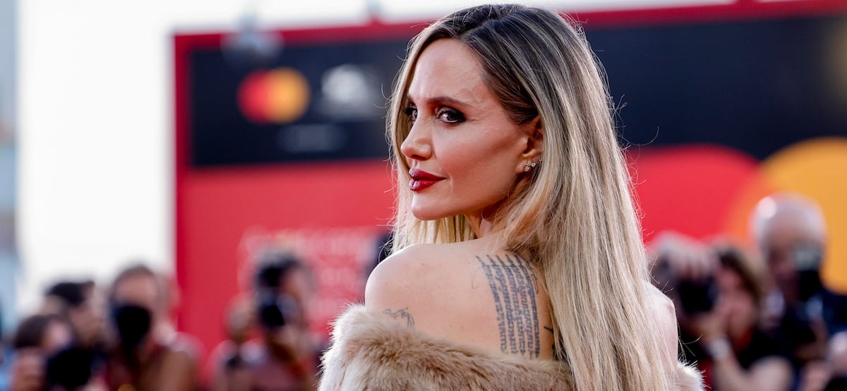 Con labial rojo y un traje que deja ver los tatuajes en su espalda, Angelina Jolie aparece en el Festival de Cine de Venecia