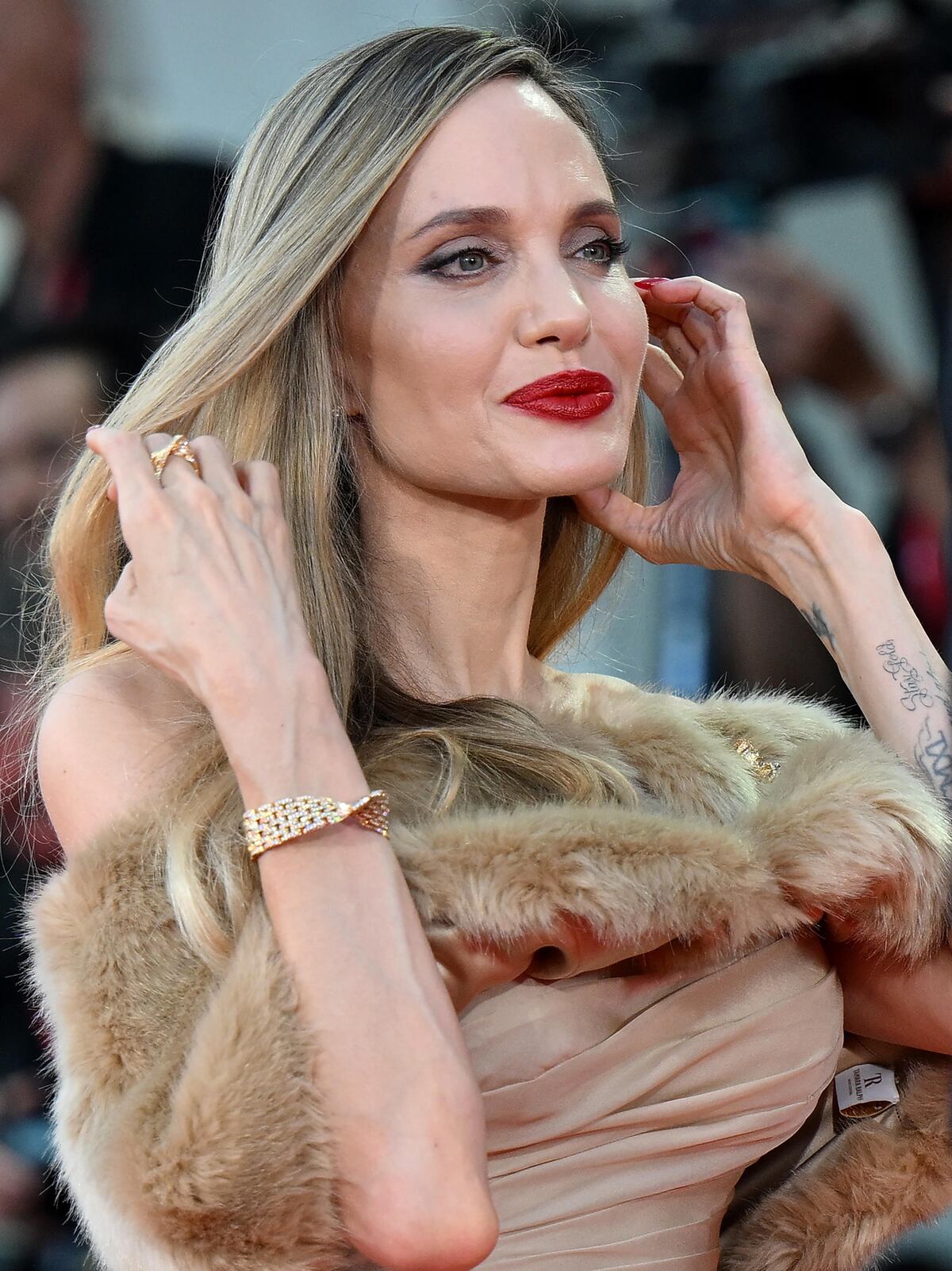 Con labial rojo y un traje que deja ver los tatuajes en su espalda, Angelina Jolie aparece en el Festival de Cine de Venecia